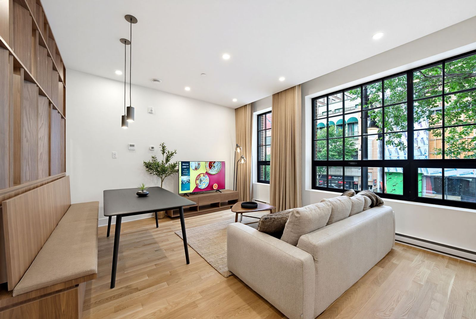 Bright open living room with sofa, dining table and large black-framed windows