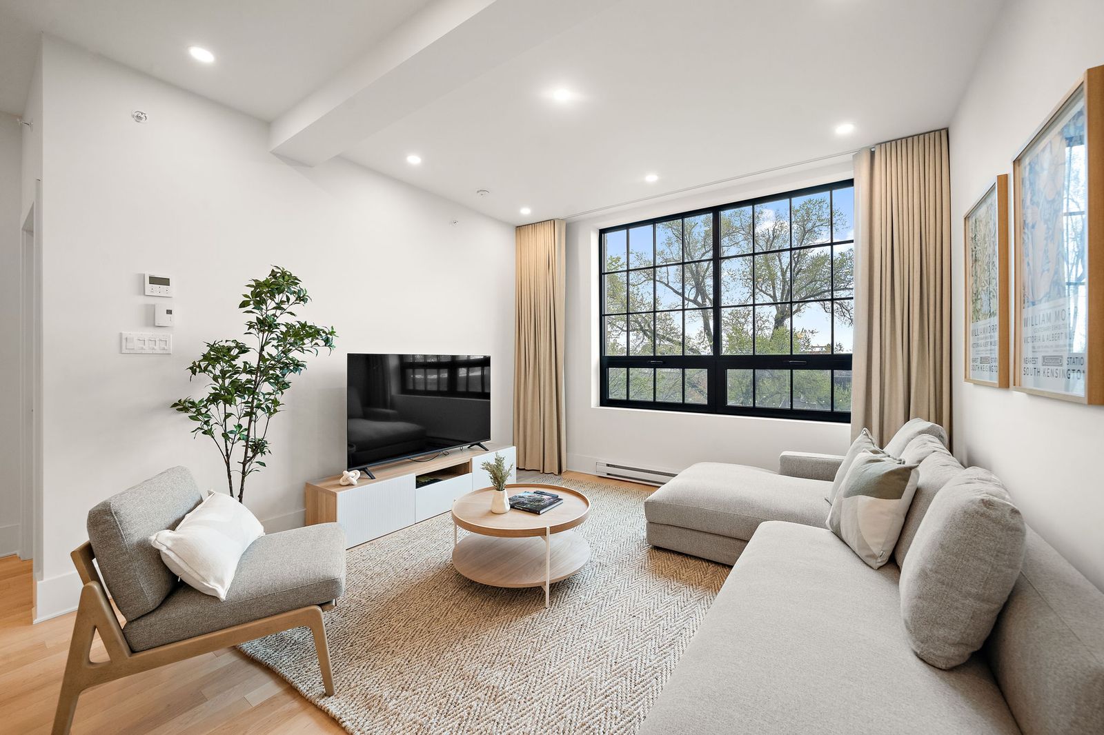 Sunlit living room with sofa, lounge chair and tall windows